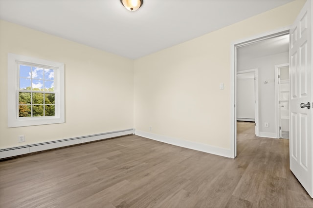 empty room with a baseboard radiator and light hardwood / wood-style floors