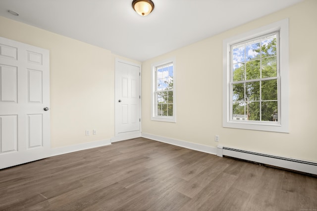 empty room with wood-type flooring and a baseboard heating unit