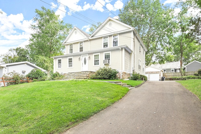 front facade featuring a front yard, a garage, and an outbuilding