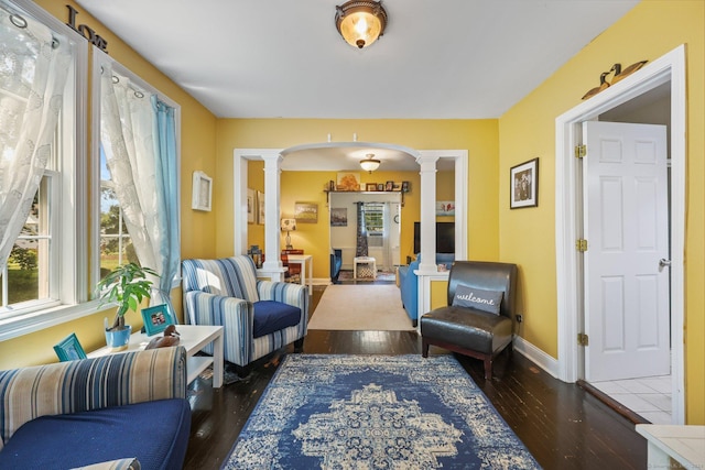 living area with ornate columns and dark hardwood / wood-style floors