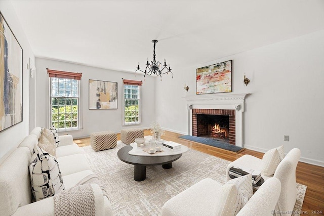 living room featuring hardwood / wood-style flooring, a brick fireplace, and a chandelier