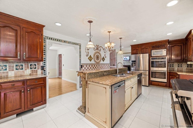 kitchen with appliances with stainless steel finishes, sink, hanging light fixtures, and light tile patterned floors