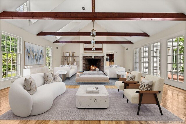 living room with light hardwood / wood-style flooring and vaulted ceiling with beams