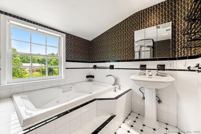 bathroom with tile walls, tiled tub, and tile patterned flooring