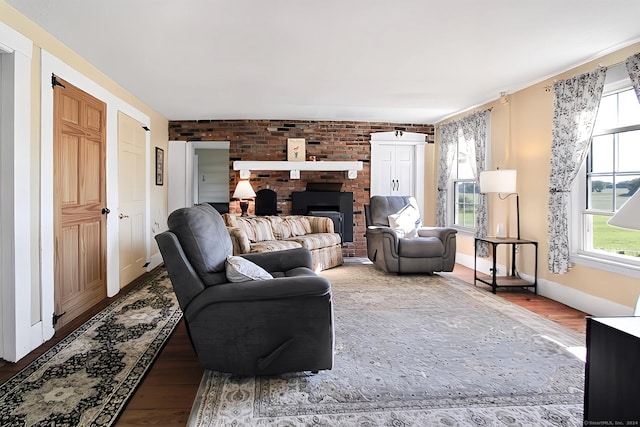 living room with a wealth of natural light, hardwood / wood-style floors, and brick wall