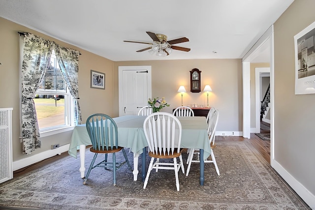 dining space with ceiling fan and dark wood-type flooring