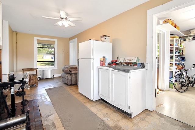 kitchen with radiator, ceiling fan, white fridge, white cabinetry, and washer / clothes dryer