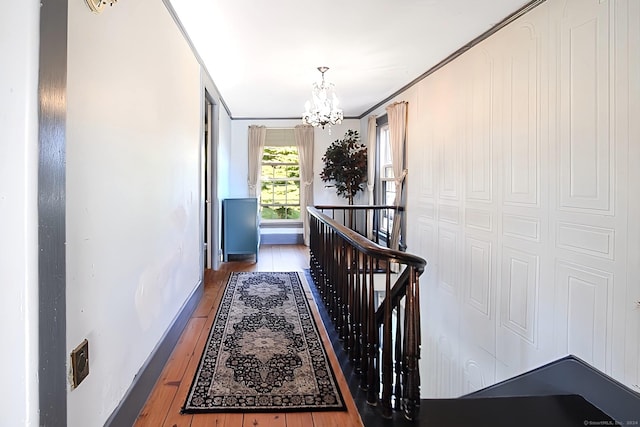 hallway featuring hardwood / wood-style floors, ornamental molding, and a chandelier