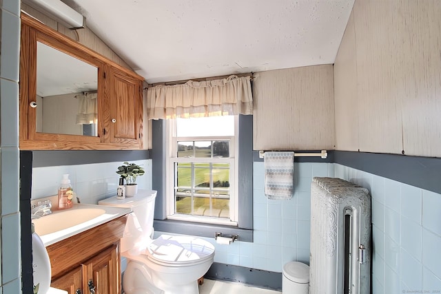 bathroom featuring vanity, toilet, tile walls, and radiator