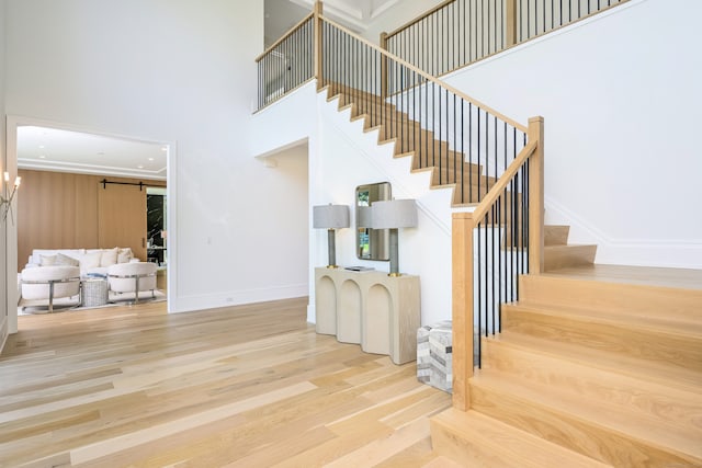 staircase featuring wood-type flooring, a barn door, and a high ceiling