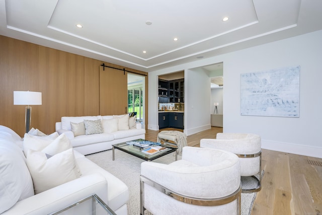 living room with light hardwood / wood-style floors and a raised ceiling