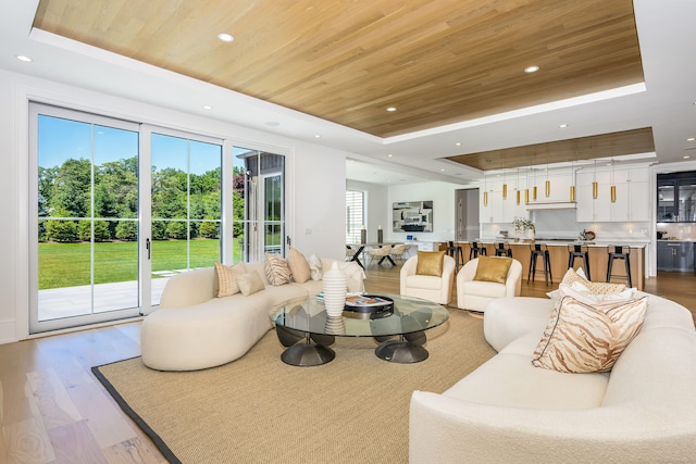 living room featuring a raised ceiling, wood ceiling, and light hardwood / wood-style flooring