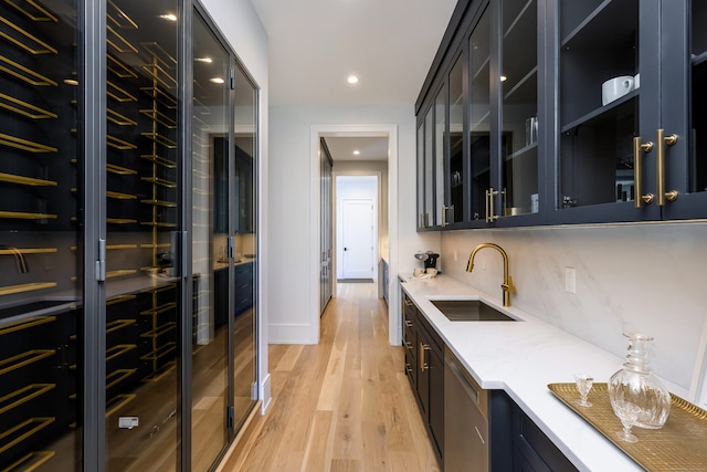 bar featuring tasteful backsplash, light hardwood / wood-style flooring, and sink