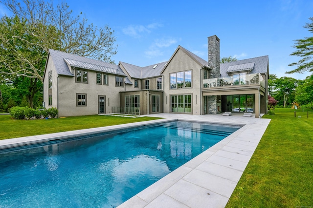 back of property featuring a yard, a patio area, and a balcony