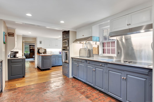 kitchen featuring stainless steel counters, white cabinetry, stainless steel appliances, and plenty of natural light