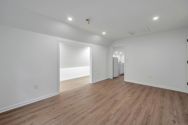 spare room featuring sink, lofted ceiling, and light wood-type flooring