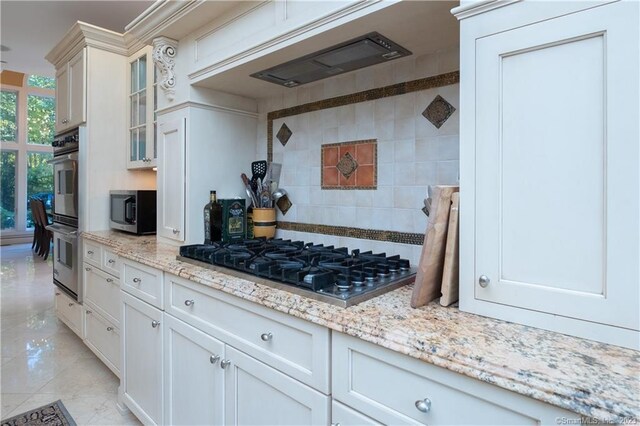 kitchen with light stone countertops, light tile floors, custom exhaust hood, and appliances with stainless steel finishes