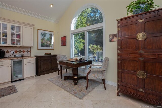 dining room featuring beverage cooler, high vaulted ceiling, ornamental molding, and light tile floors