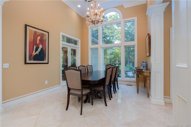 tiled dining space with a notable chandelier, ornamental molding, a towering ceiling, and ornate columns