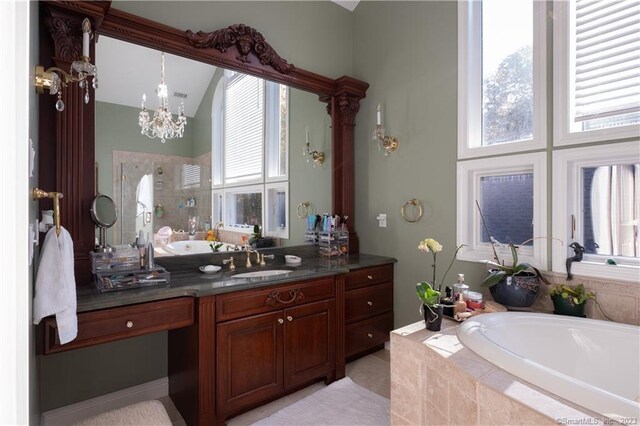 bathroom featuring tiled bath, vanity, and a chandelier