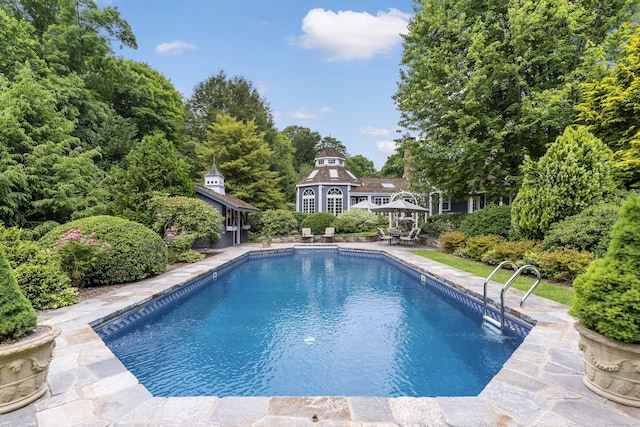 view of swimming pool featuring a patio, a gazebo, and an outbuilding