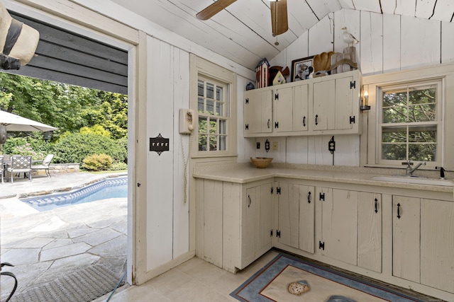 kitchen with vaulted ceiling, sink, white cabinets, and ceiling fan