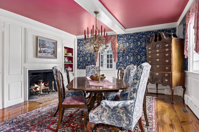 dining area with an inviting chandelier, hardwood / wood-style floors, a baseboard radiator, and ornamental molding