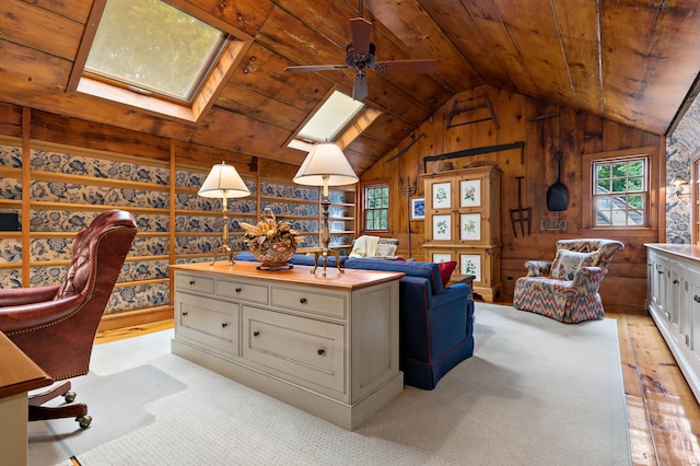 home office featuring ceiling fan, wood ceiling, vaulted ceiling with skylight, and wood walls