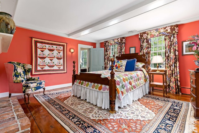 bedroom featuring a baseboard radiator, beam ceiling, and hardwood / wood-style floors