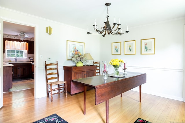 dining space with crown molding, light hardwood / wood-style flooring, ceiling fan with notable chandelier, and sink