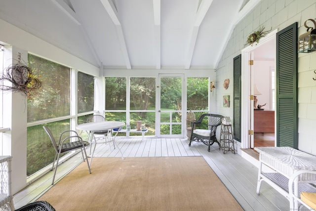 sunroom / solarium featuring vaulted ceiling with beams