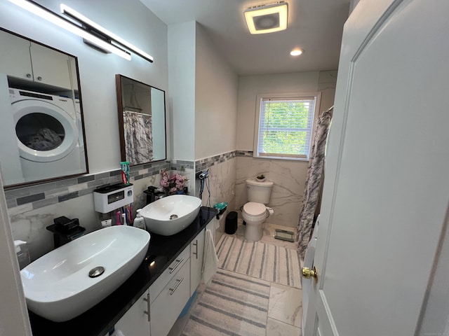 bathroom with vanity, washer / clothes dryer, toilet, and tile walls