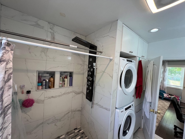 laundry room featuring cabinets and stacked washer and clothes dryer