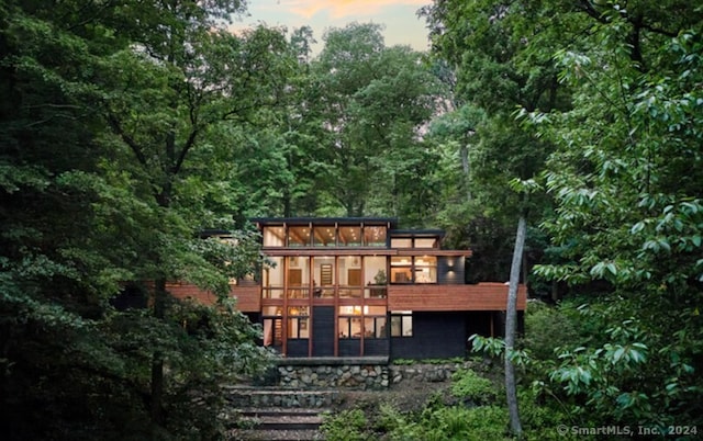 back house at dusk with a sunroom