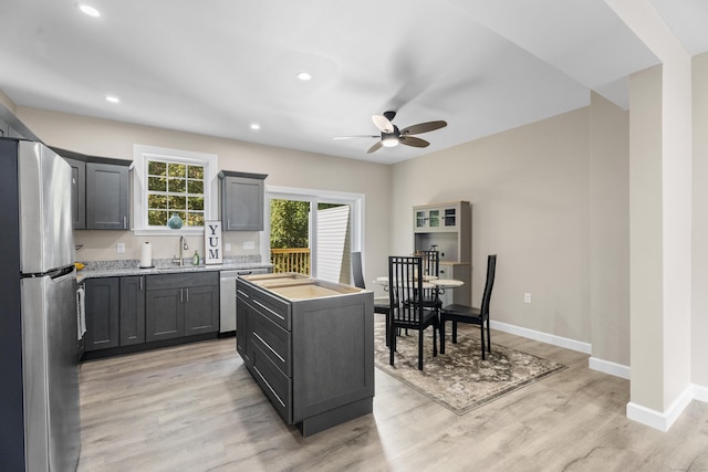 203 Winding Hollow Rd, Groton, CT 06340 - kitchen featuring a ceiling fan, a center island, light wood finished floors, a sink, and appliances with stainless steel finishes
