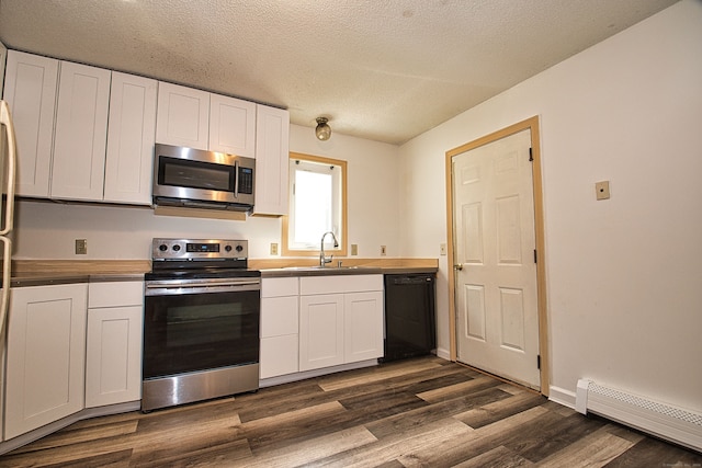 kitchen with white cabinets, baseboard heating, stainless steel appliances, and dark wood-type flooring