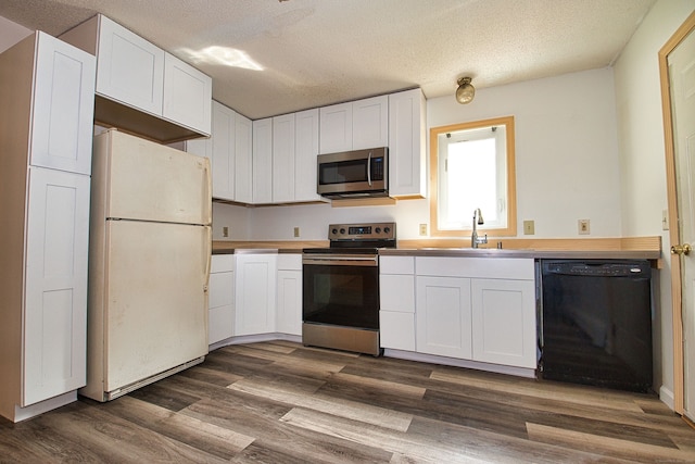 kitchen with dark hardwood / wood-style flooring, white cabinets, a textured ceiling, and appliances with stainless steel finishes