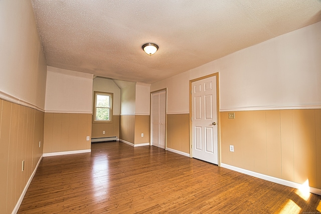 spare room with a textured ceiling, dark wood-type flooring, and a baseboard radiator