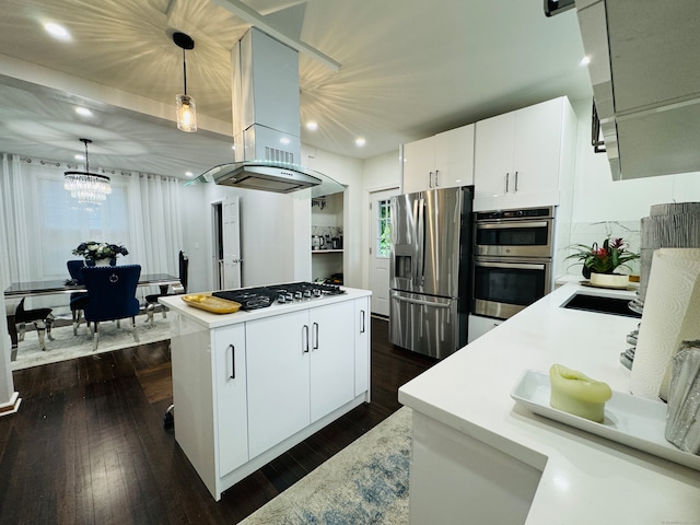 kitchen with island range hood, pendant lighting, dark wood-type flooring, white cabinets, and appliances with stainless steel finishes