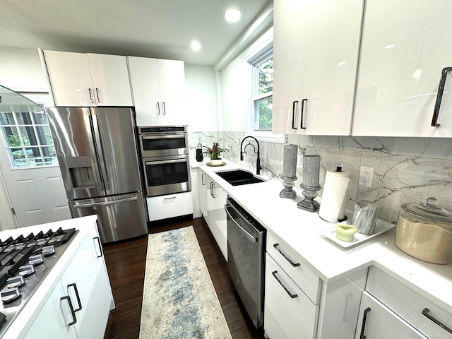 kitchen with stainless steel appliances, backsplash, dark wood-type flooring, white cabinets, and sink