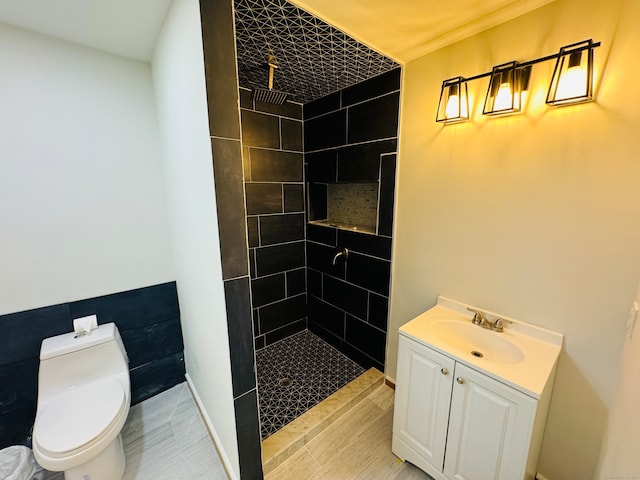 bathroom with tiled shower, vanity, and toilet