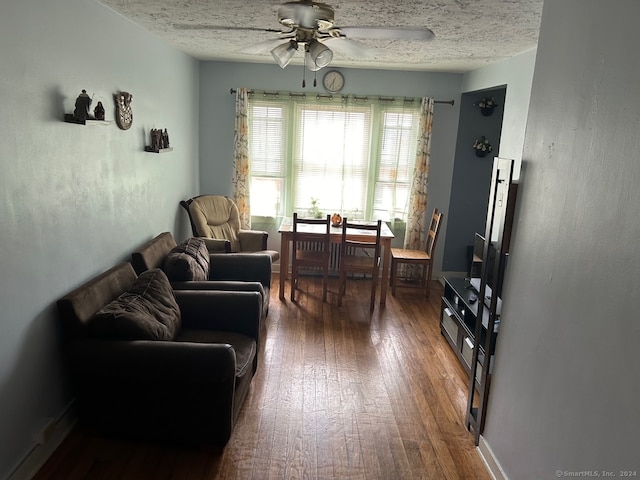 living room featuring a textured ceiling, ceiling fan, and dark hardwood / wood-style flooring