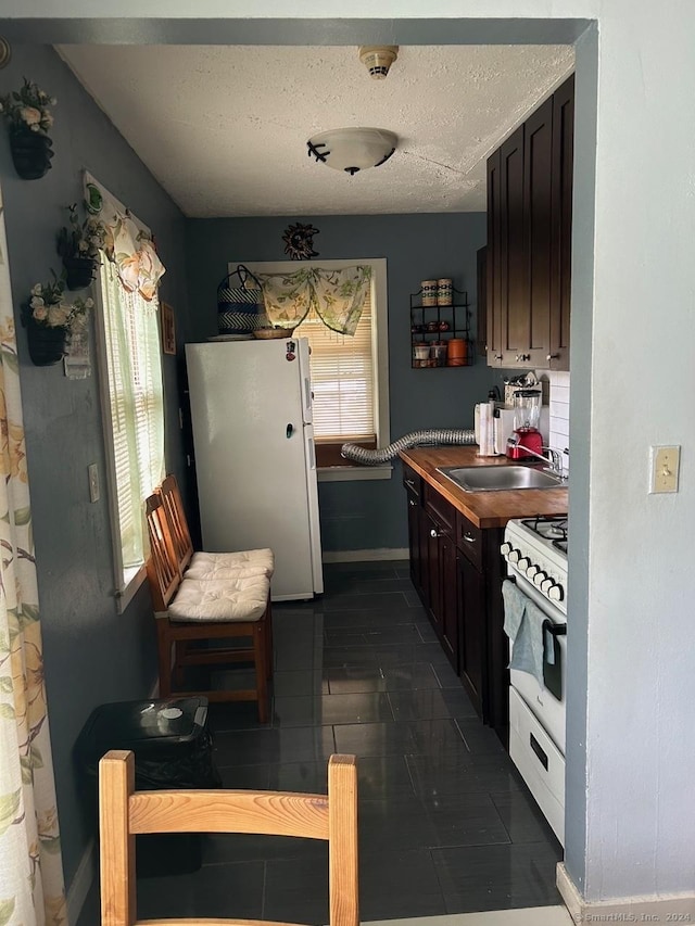 260 Success Ave Unit 21, Bridgeport, CT 06610 - kitchen with white appliances, a sink, baseboards, dark tile patterned flooring, and a textured ceiling
