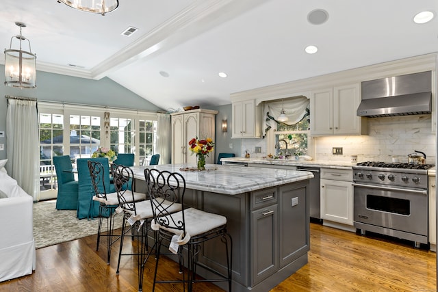 kitchen featuring wall chimney exhaust hood, a center island, stainless steel appliances, and a healthy amount of sunlight