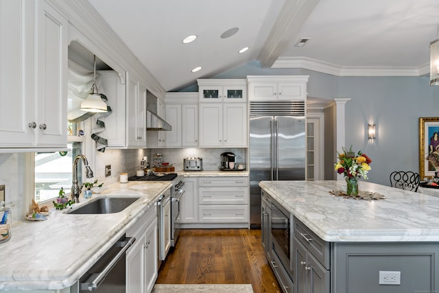 kitchen with built in appliances, hanging light fixtures, dark hardwood / wood-style flooring, white cabinets, and tasteful backsplash