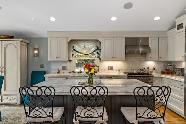 kitchen featuring light stone countertops, wall chimney exhaust hood, and a center island