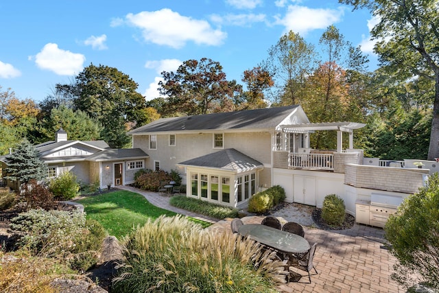 rear view of house with a patio, a yard, and an outdoor kitchen