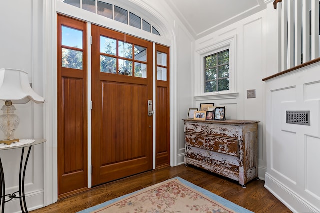 foyer entrance with ornamental molding, dark hardwood / wood-style floors, and a healthy amount of sunlight