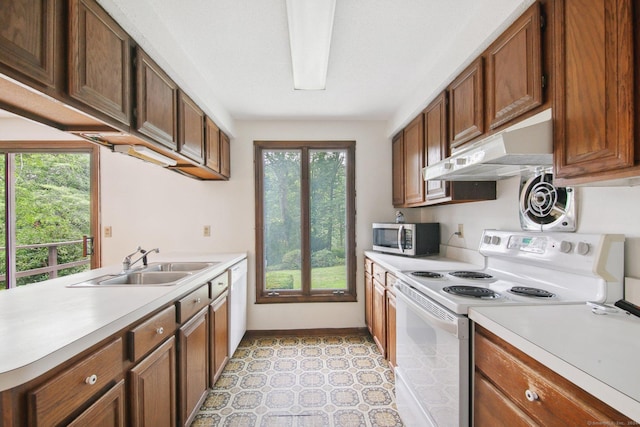 kitchen featuring white appliances, kitchen peninsula, and sink