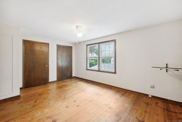 unfurnished bedroom with ceiling fan, multiple closets, and light wood-type flooring